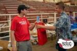 BHC grad hands off a bag to another person in an indoor arena